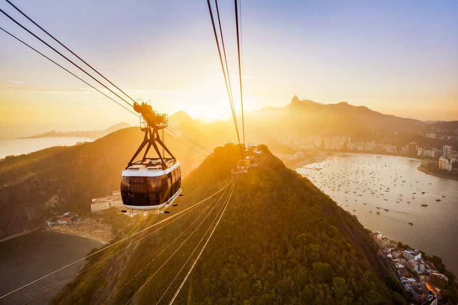 The Sugarloaf cable car crossing above Guanabara Bay at sunset